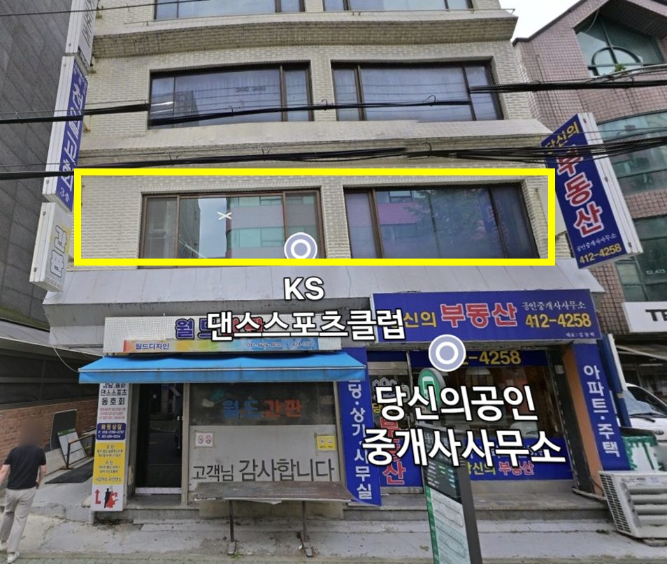 별빛공간 건물 앞모습. 2층 창문에 노란 테두리 표시, 1층에 당신의부동산과 월드간판 간판